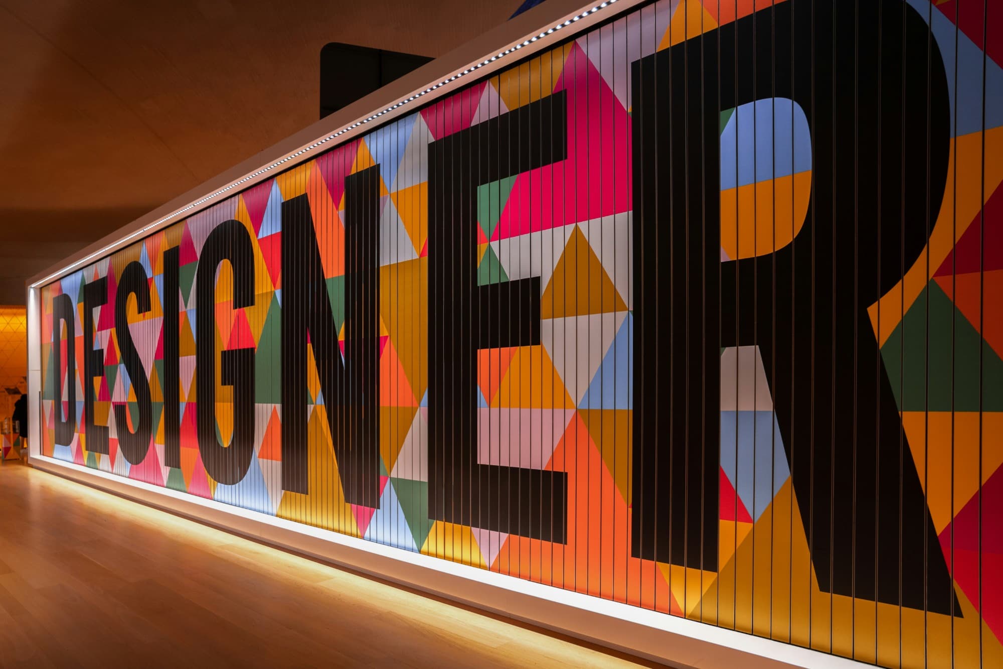 Colourful geometric wall mural spelling DESIGNER